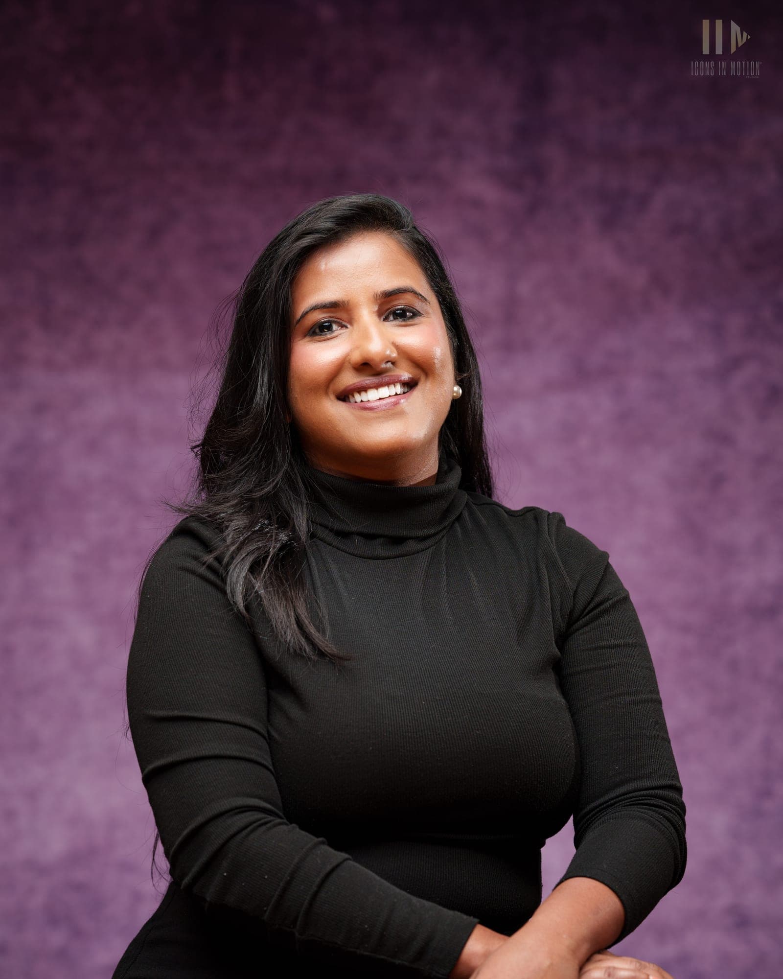 Studio headshot of a person in a black turtleneck, head tilted, laughing