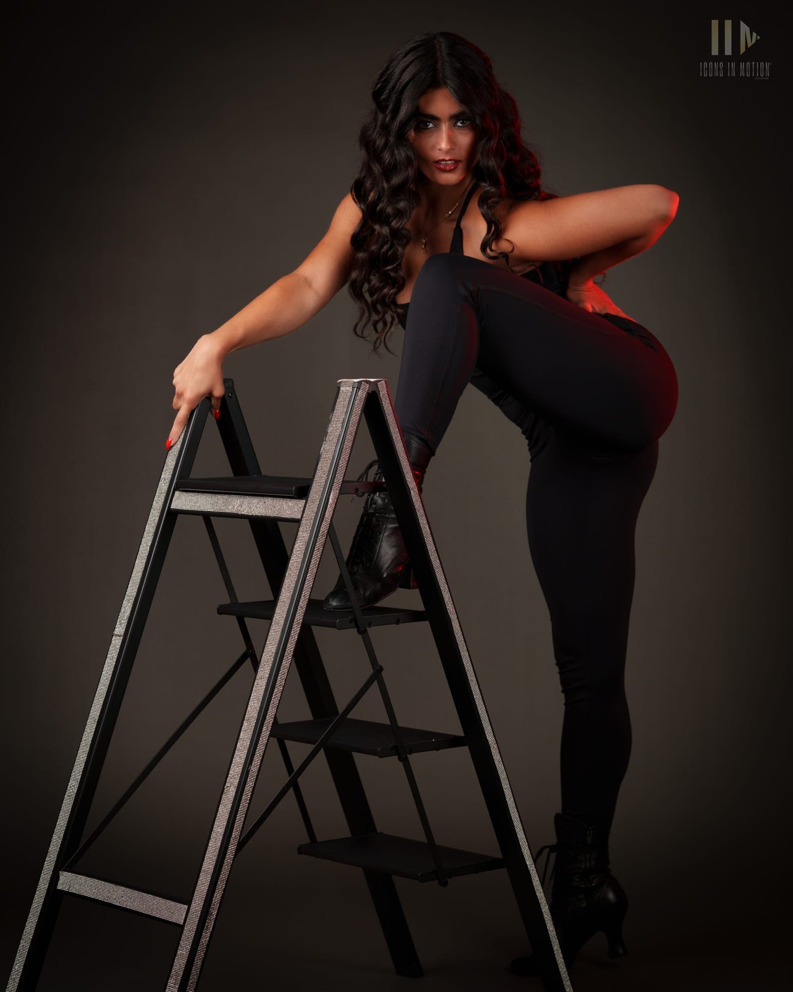 Dancer in black posed with one leg extended along a step ladder