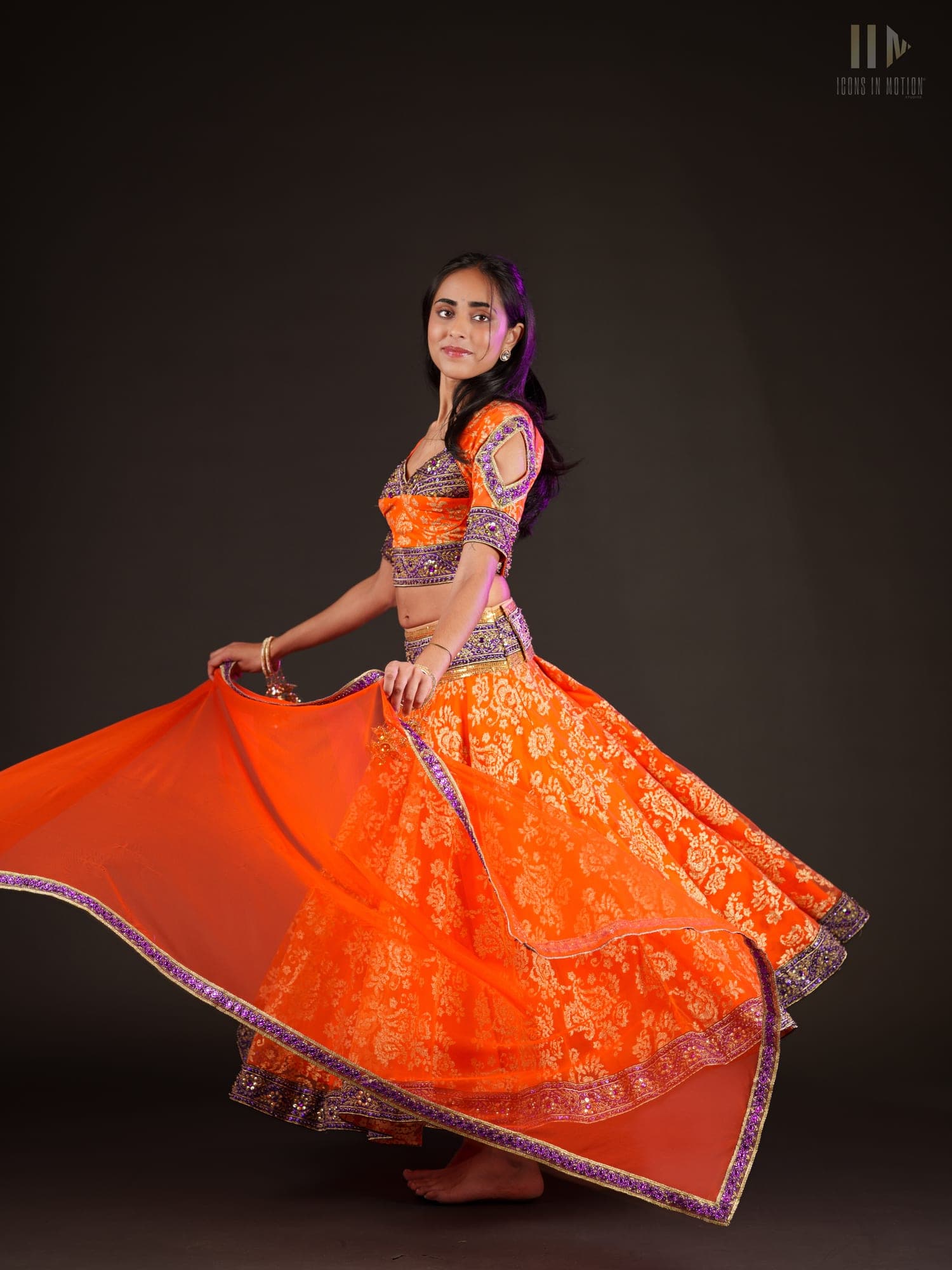 Dancer spinning so an embroidered orange skirt flares into a circle