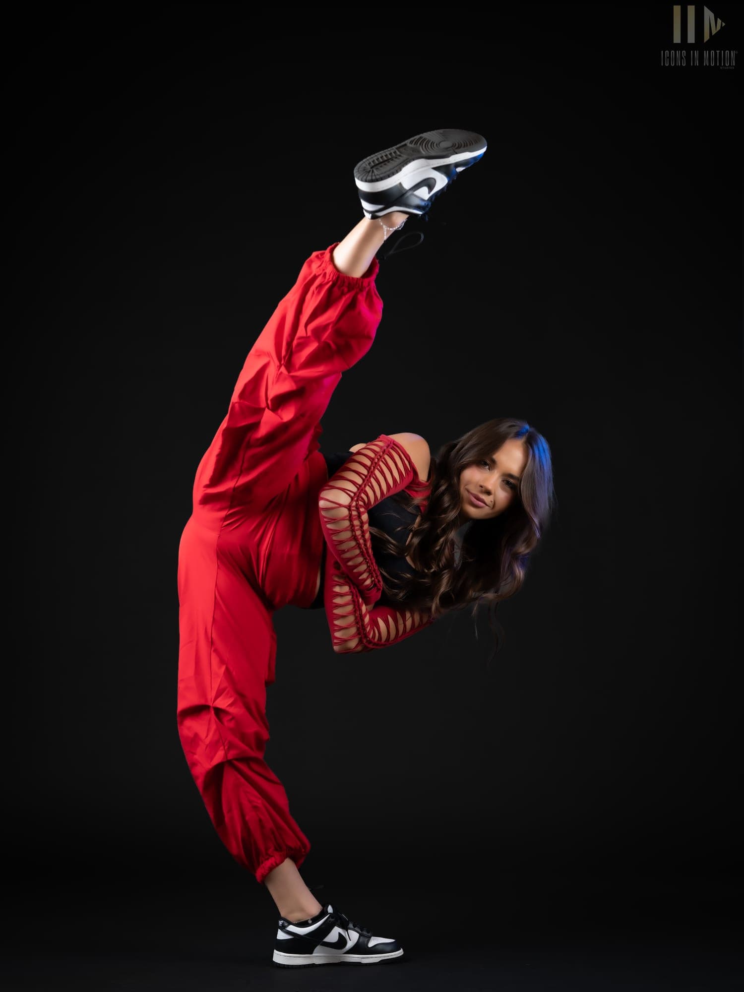 Dancer in red folded into a high kick, hair falling loose