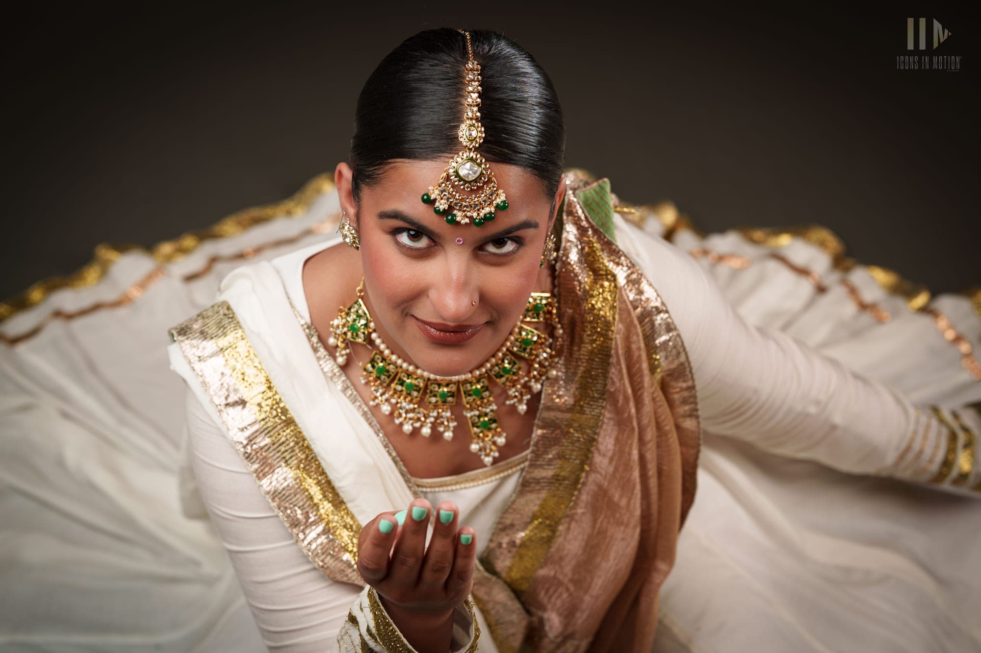 Classical dancer seated in white and gold, hands held in a mudra