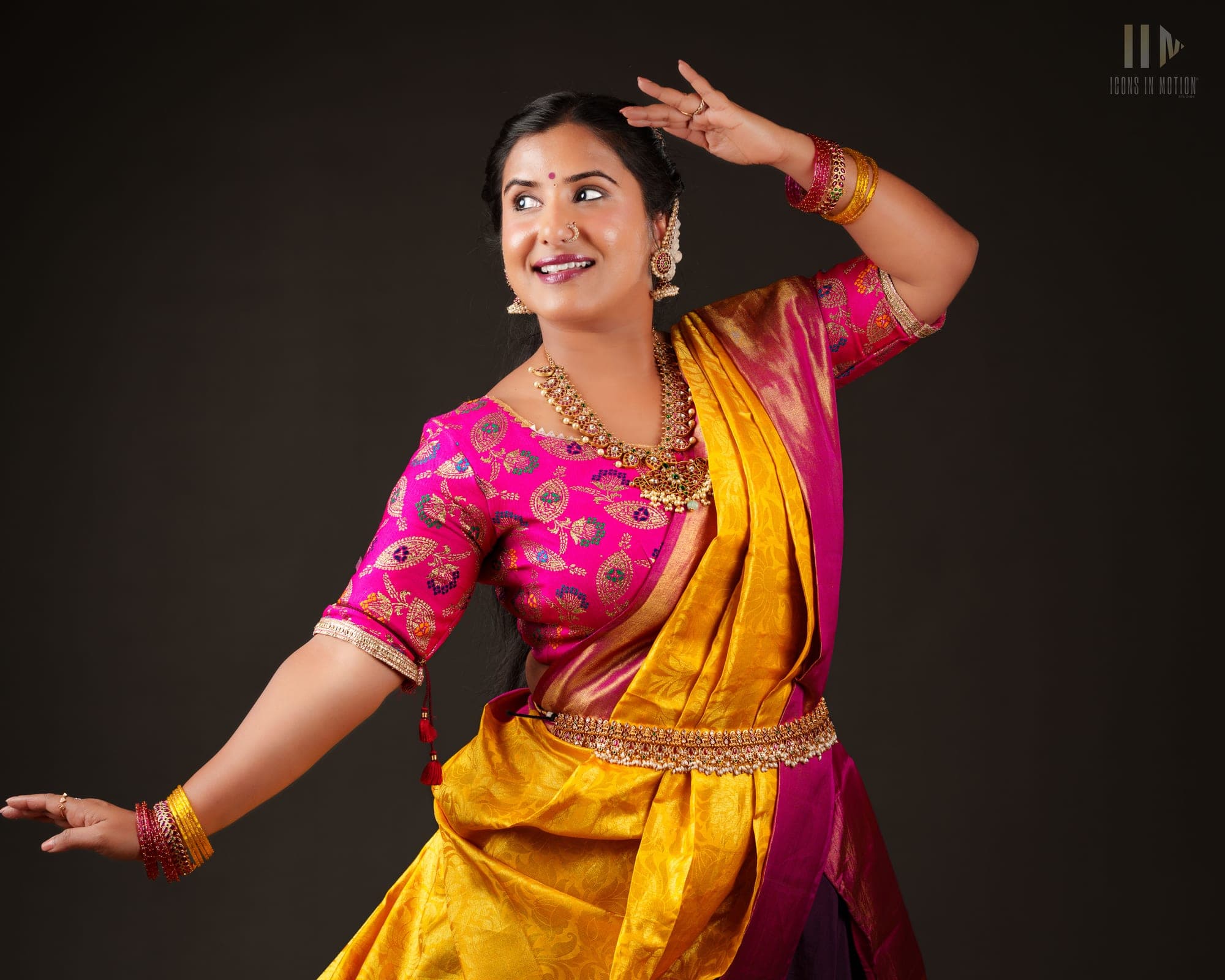 Classical dancer in a pink and gold silk saree holding a pose