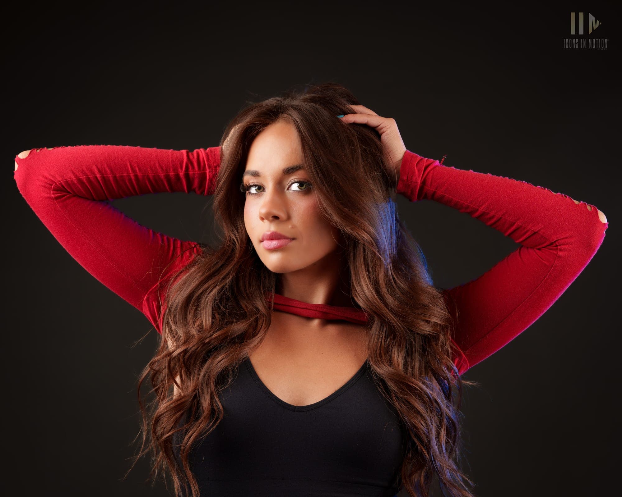 Portrait of a dancer in red sleeves with hands raised into their hair