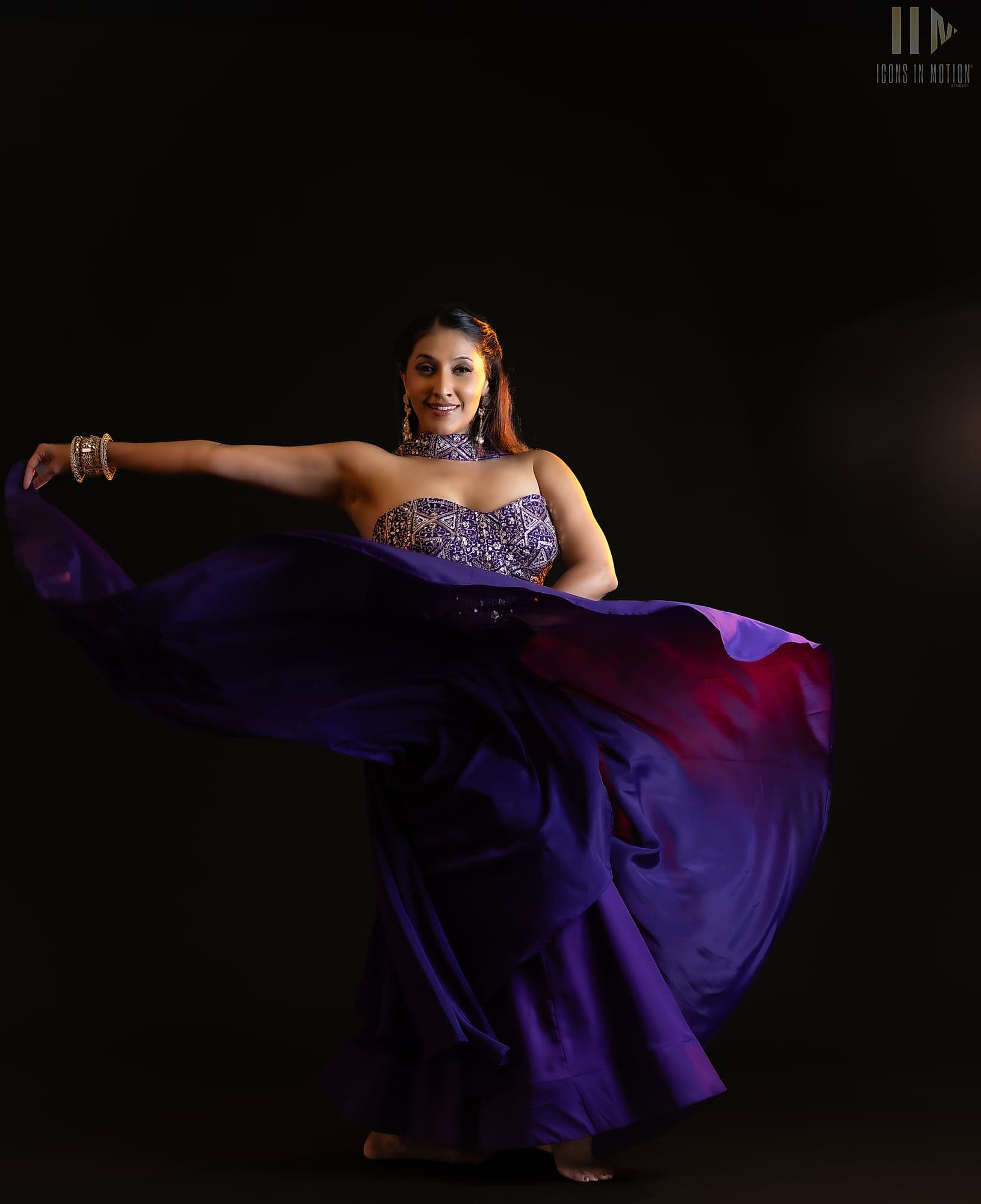 Dancer sweeping a purple lehenga skirt into a wide arc, one arm outstretched